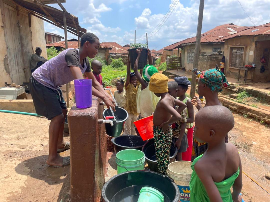 A crowd of children and residents gathering with buckets at the new tap