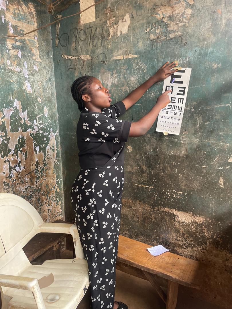A volunteer holding up a Snellen eye chart for a patient