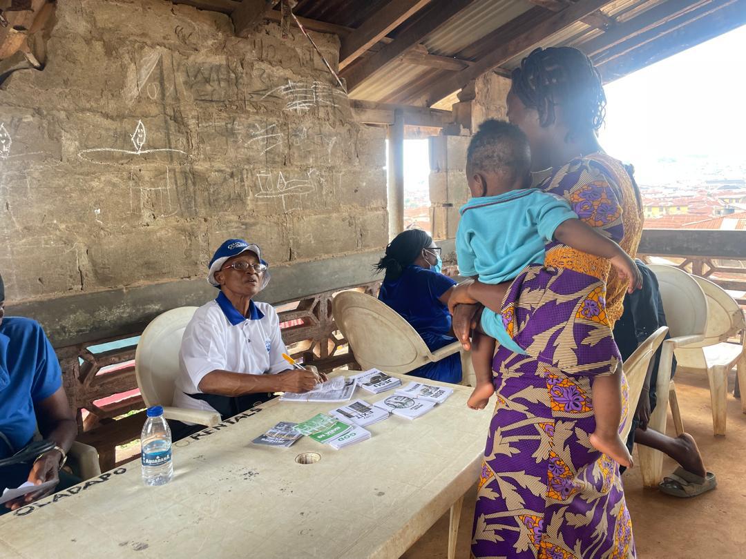 An elderly volunteer registering a mother and toddler