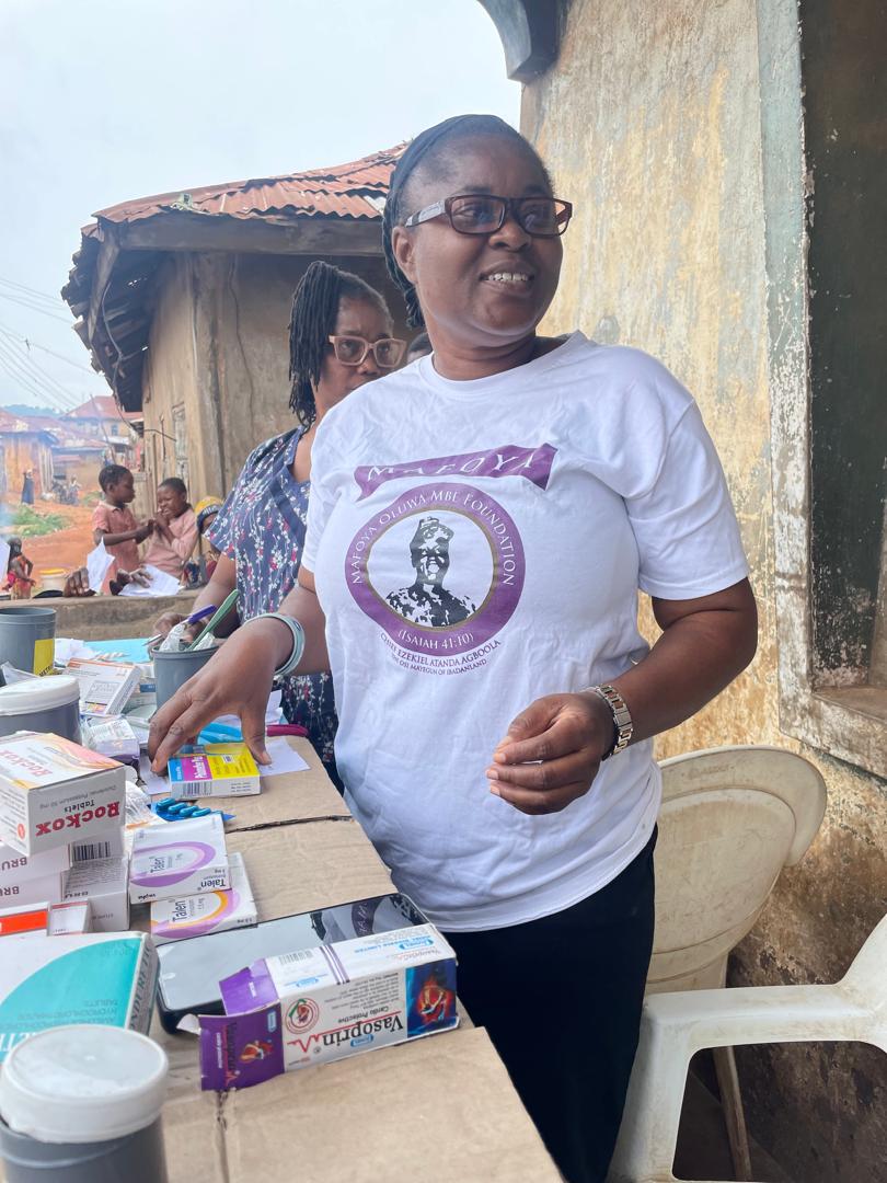 A volunteer in a Mafoya Foundation shirt sorting medication for dispensing