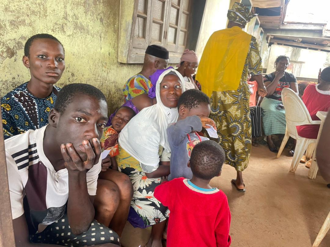 A family waiting together indoors, a young man looking toward the camera